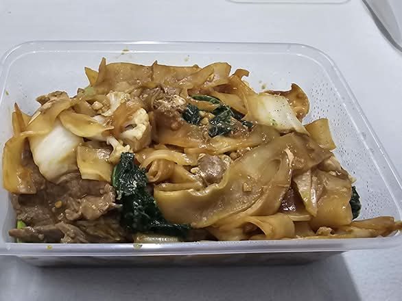 Pad see ew with flat rice noodles, beef and Chinese broccoli, in a takeaway box